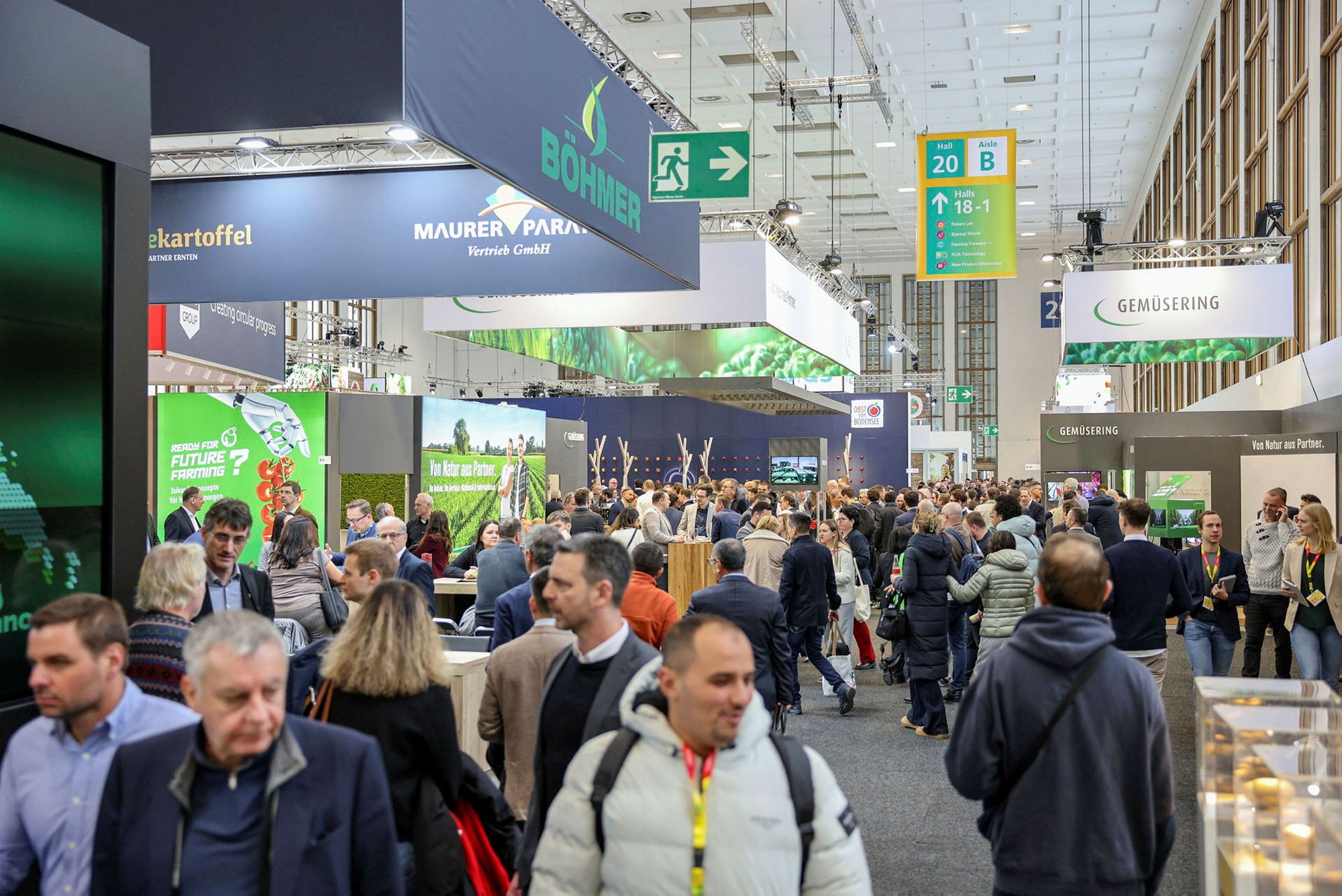 Trade visitors filling the aisle between exhibitor stands in a fresh produce hall.