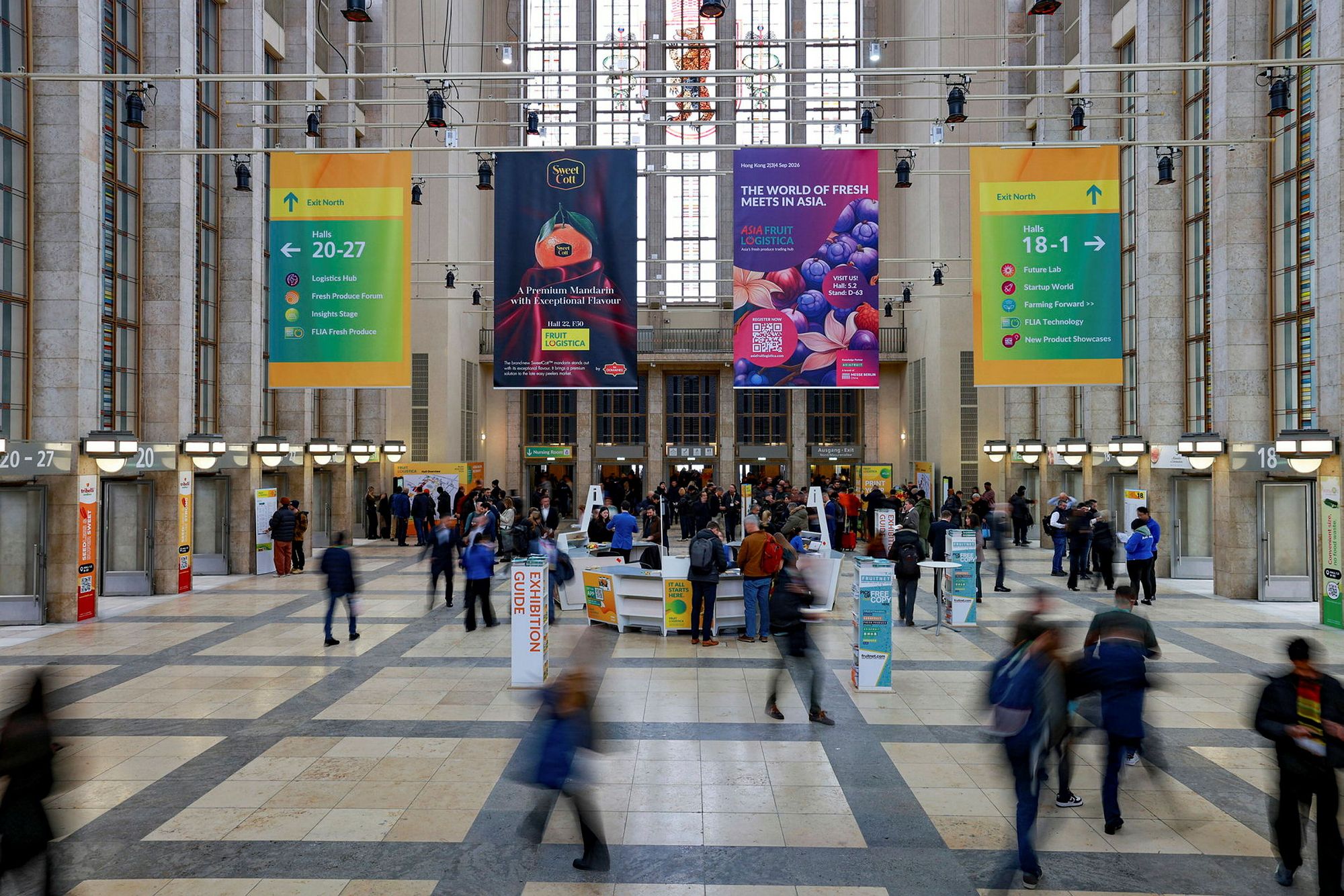 Visitors arriving through the main entrance concourse of FRUIT LOGISTICA in Berlin, hall banners suspended overhead.