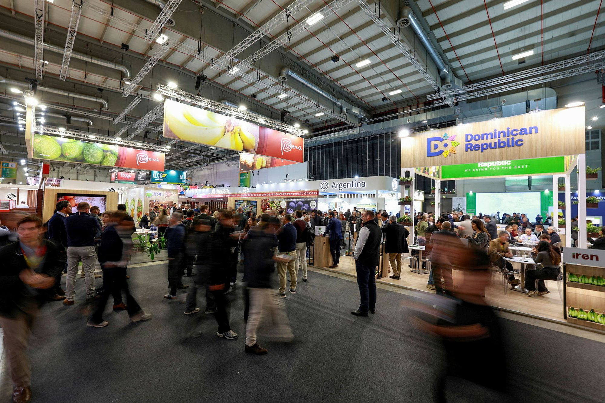 Trade visitors moving along a busy exhibition aisle between national pavilion stands.