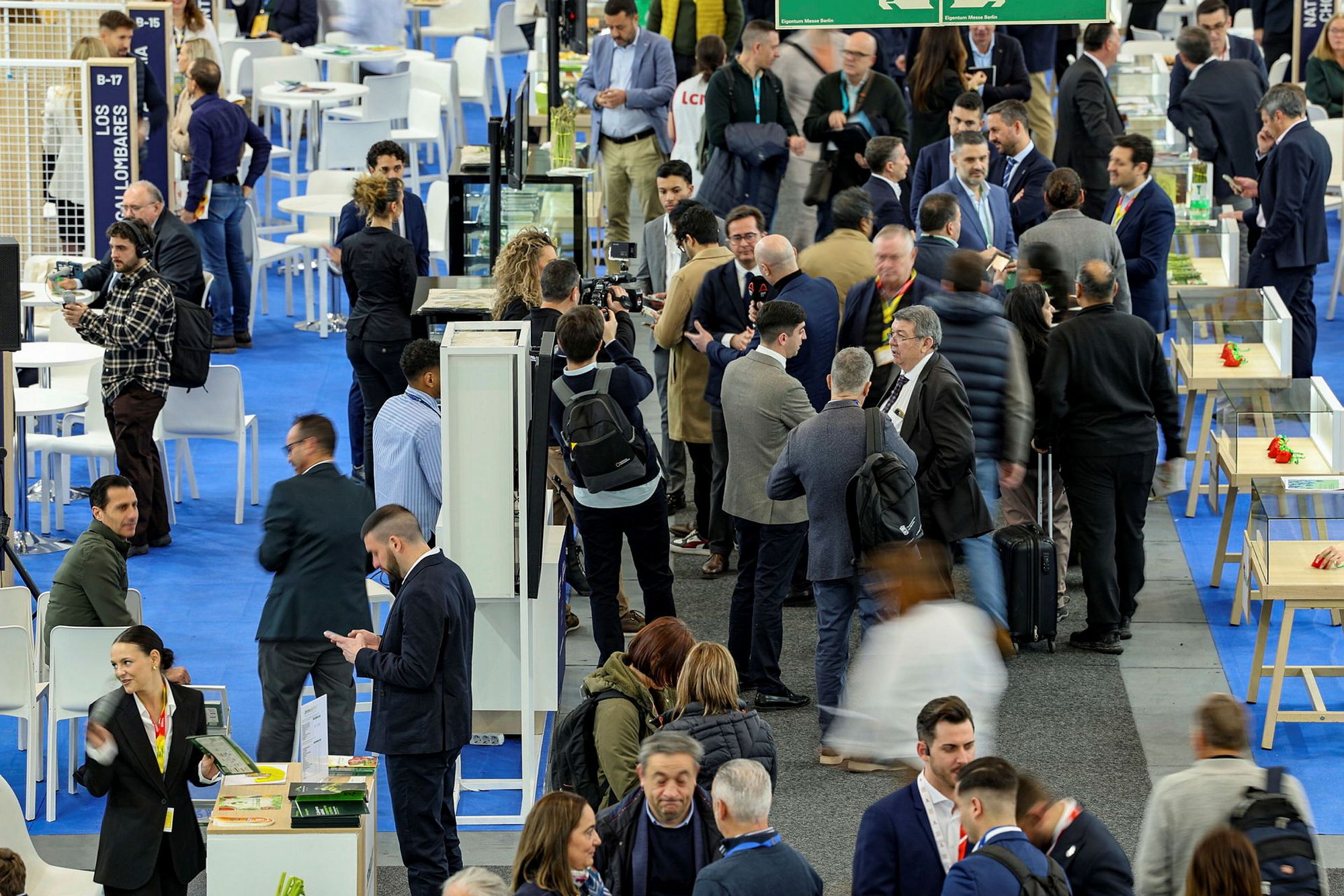 A dense crowd of trade professionals meeting between exhibition stands on the show floor.